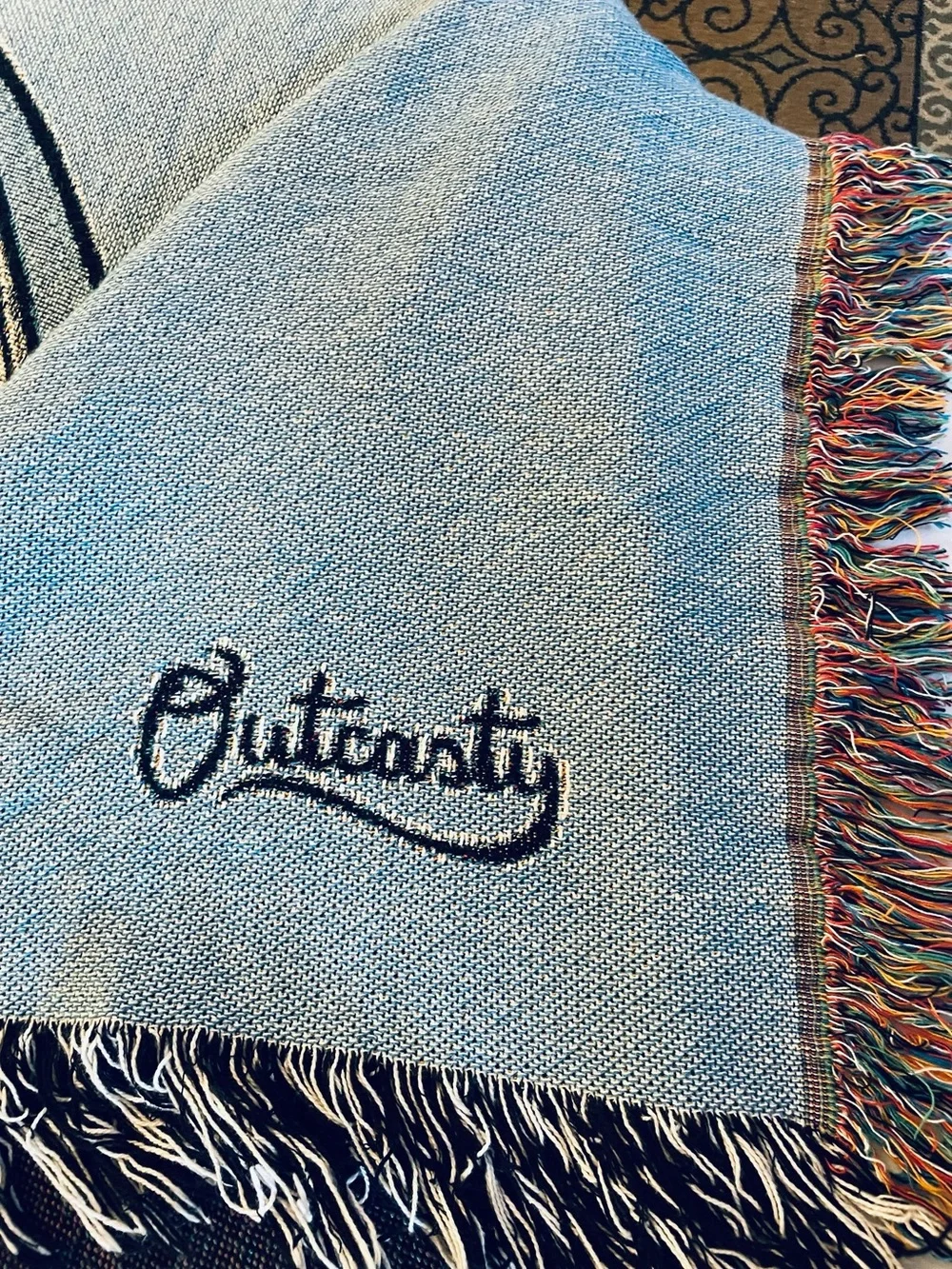 Outcasty cotton throw, relaxing sloth with book, shown on a Queen size bed